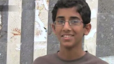 Abdulrahman Al-Aulaqi, a teenage boy with combed hair wearing glasses, smiling
