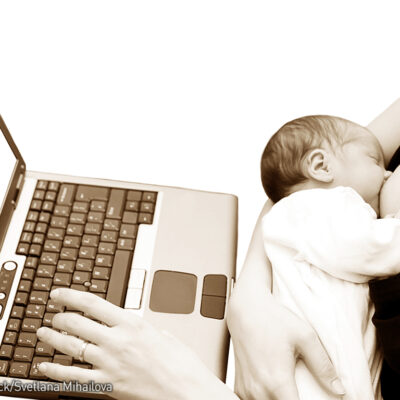 Breastfeeding baby with mom at the laptop