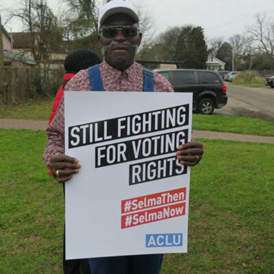 Activist at Selma holding sign: Still Fighting for Voting Rights #SelmaThen #SelmaNow