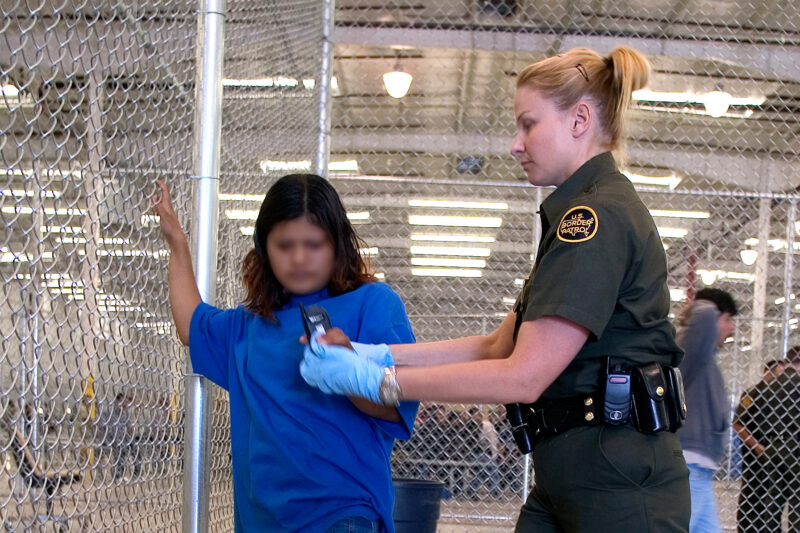 CBP Border Patrol agent conducts a pat down of a female Mexican being placed in a holding facility.