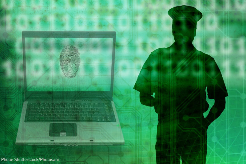 Silhouette of a police officer beside a laptop with fingerprint