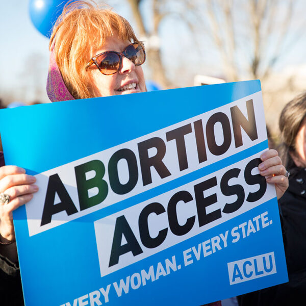 Woman holding "Abortion Access" poster at rally