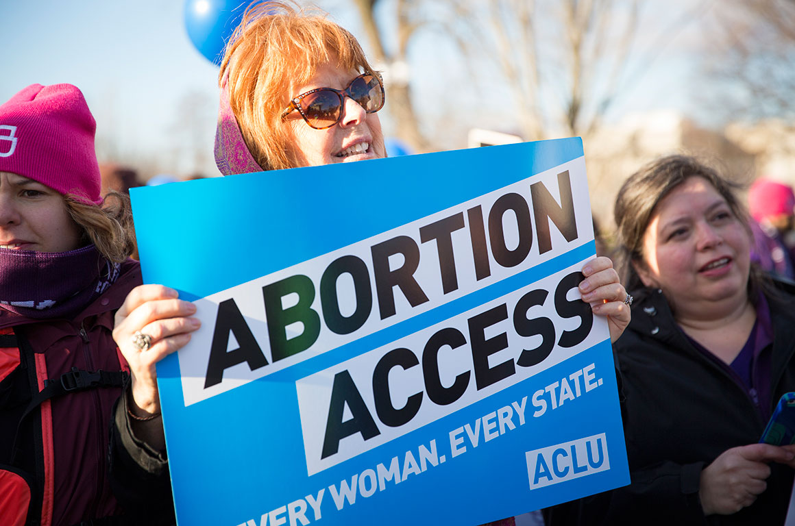 Woman holding "Abortion Access" poster at rally