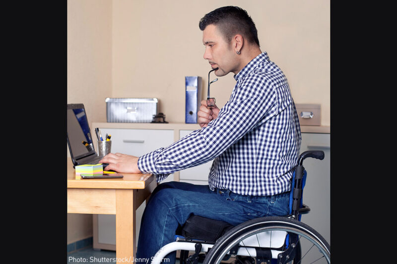 Man sitting in a wheelchair using a laptop
