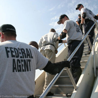Federal agents deporting individuals on a plane