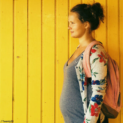 Pregnant woman in front of yellow background.
