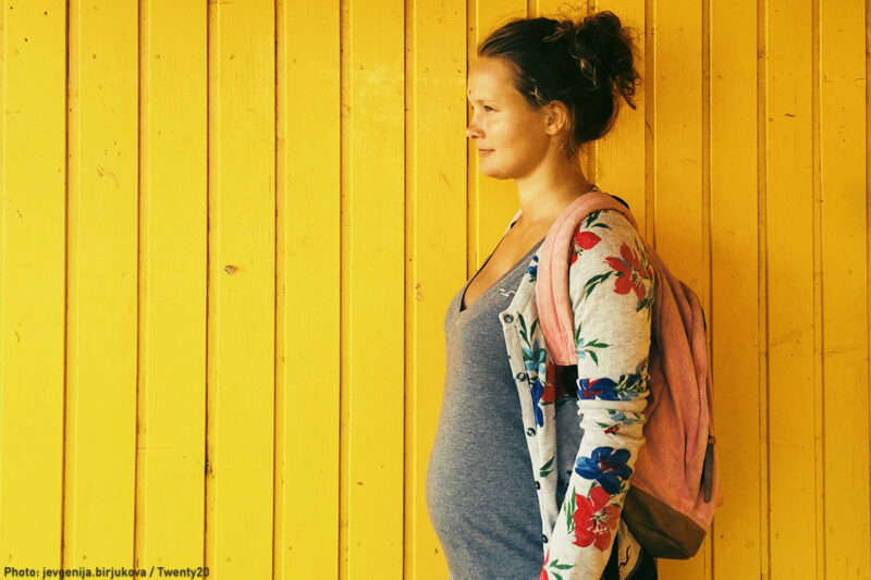 Pregnant woman in front of yellow background.