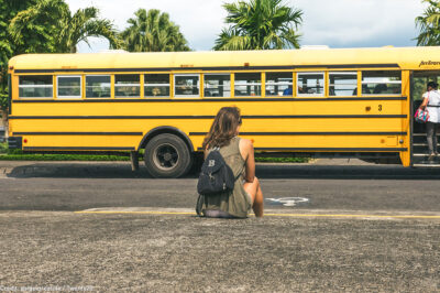 Girl sitting outside with school bus