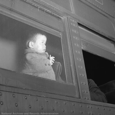 A young child of Japanese ancestry evacuates by train to internment