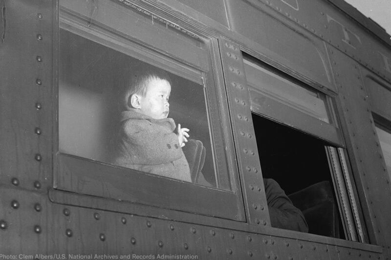 A young child of Japanese ancestry evacuates by train to internment