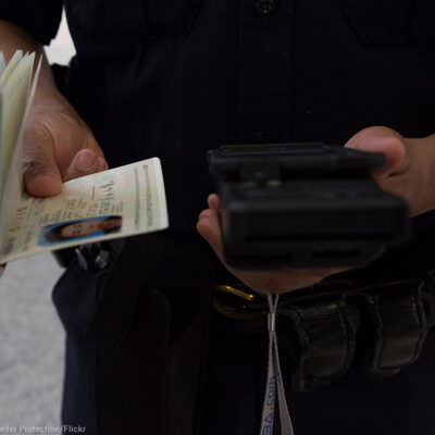 A CBP officer checks a passenger's ID