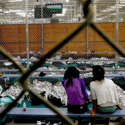 Two young girls watch a World Cup soccer match on a television from their holding area where hundreds of mostly Central American immigrant children are being processed and held