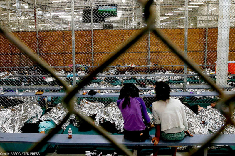 Two young girls watch a World Cup soccer match on a television from their holding area where hundreds of mostly Central American immigrant children are being processed and held