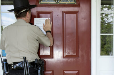 Sheriff placing eviction notice on door