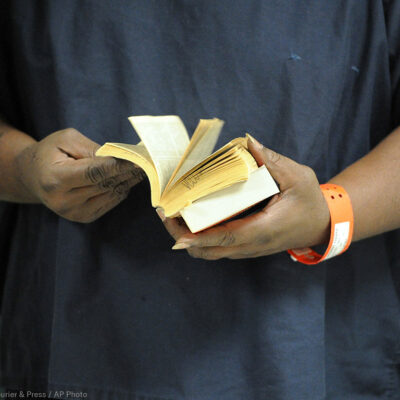 An incarcerated person thumbs through a book