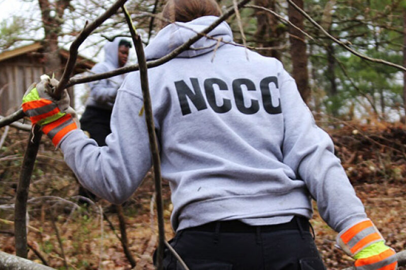 A NCCC worker hauling branches