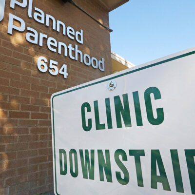 A sign with the text "Clinic Downstairs" outside a Planned Parenthood building