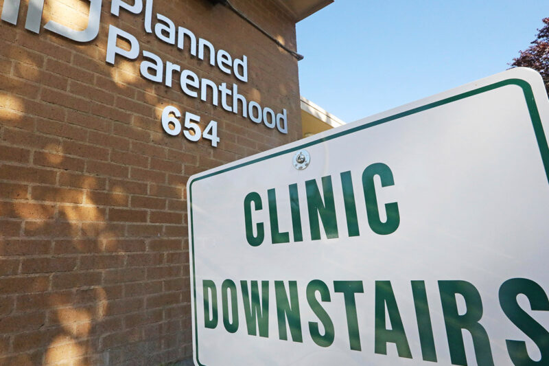 A sign with the text "Clinic Downstairs" outside a Planned Parenthood building