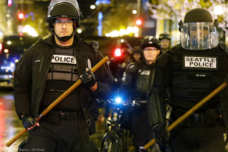 Seattle police stand guard brandishing wooden batons