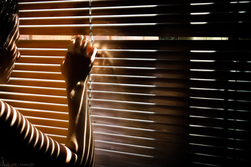 Woman peering through blinds