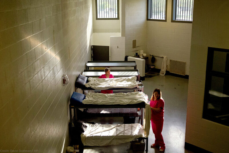Women standing by bunk in jail cell