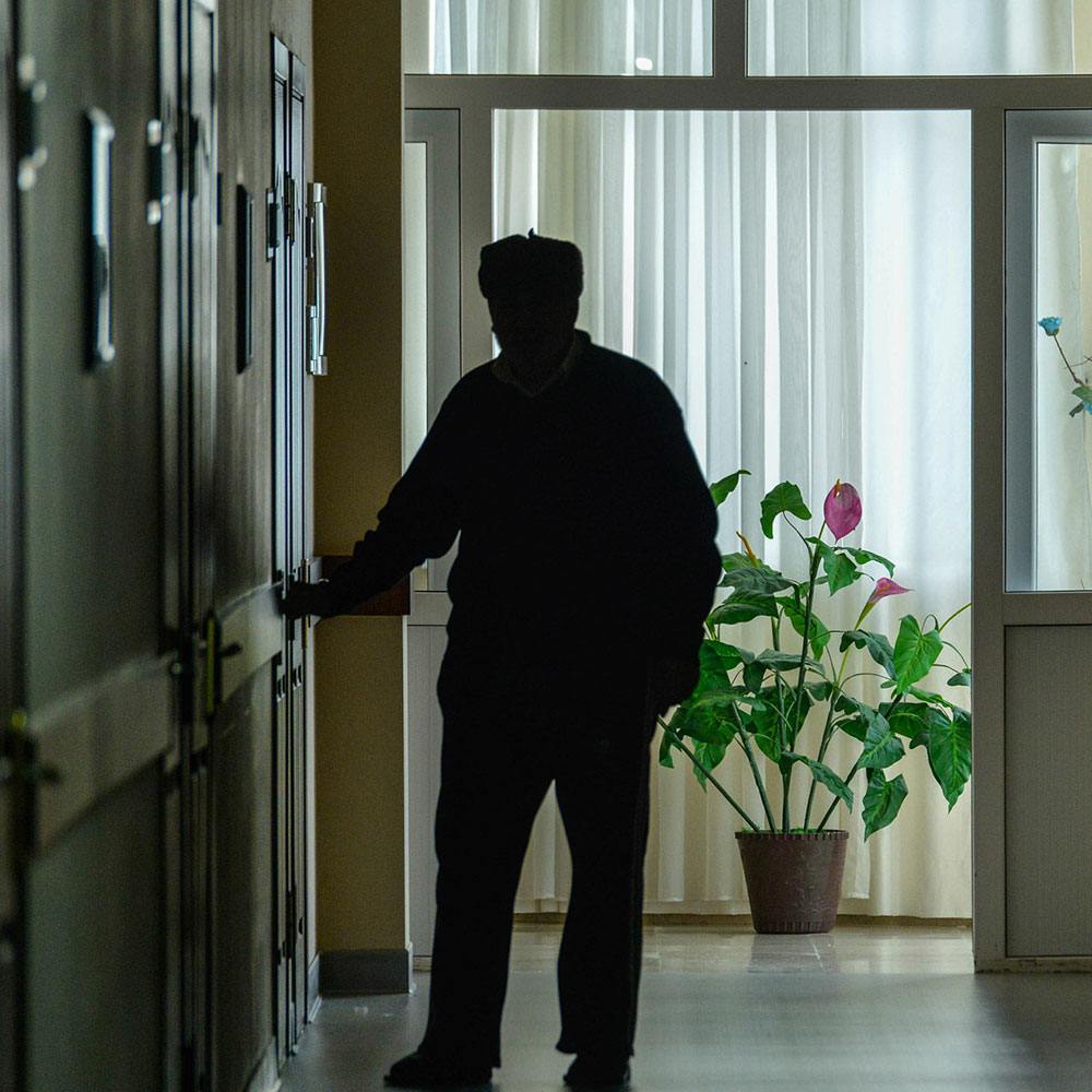A resident walks down the darkened hall of a nursing home.