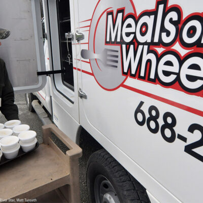 A Meals on Wheels driver loading food into a truck