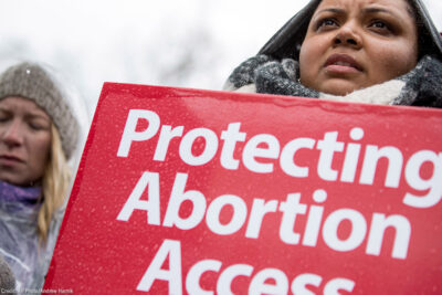 A demonstrator with a sign with the text "Protect Abortion Access"