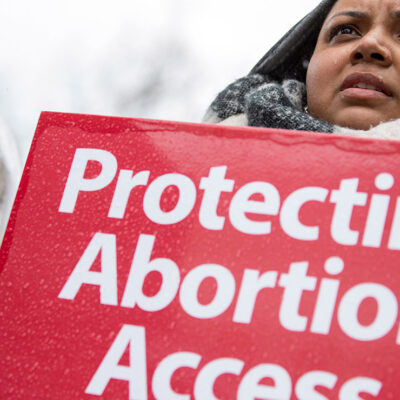 A demonstrator with a sign with the text "Protect Abortion Access"