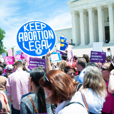 A crowd of pro-choice protesters standing outside the Supreme Court holding up signs that read "Keep Abortion Legal," and "Abortion is a Human Right" among other signs.