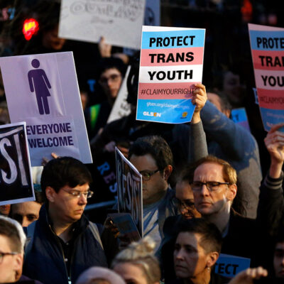 Protesters hold signs at a rally in support of transgender youth