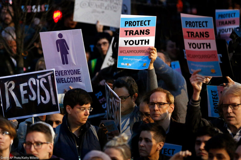 Protesters hold signs at a rally in support of transgender youth
