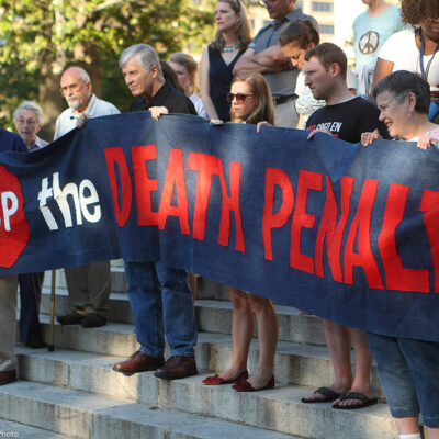 Protestors holding a banner that reads "Stop the Death Penalty" in front on Georgia's State Capital on a sunny day in 2017. Colorado just won a major feat for anti-death penalty movement with its decision to repeal the death penalty in the state.