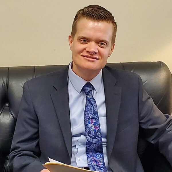 Photo of Evan Minton sitting on a couch in an office.