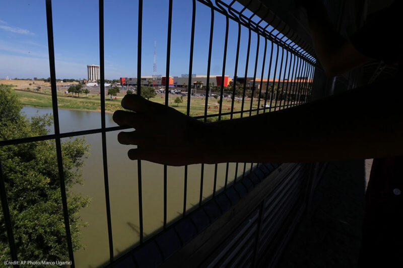 The hand of a youth from Nuevo Laredo rests on the gate as he stops to watch a train pass, above the Rio Grande river on International Bridge 1 Las Americas, a legal port of entry which connects Laredo, Texas in the U.S. with Nuevo Laredo, Mexico, Thursday, July 18, 2019.
