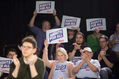 Seated members of an audience clapping and holding signs with the text "Rights for All" at the ACLU Rights for All campaign launch.