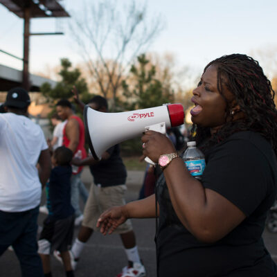 A Black woman using a megaphone at a daytime Black Lives Matter march in Minneapolis, Minnesota in response to police shooting of 18-year-old Tania Harris.