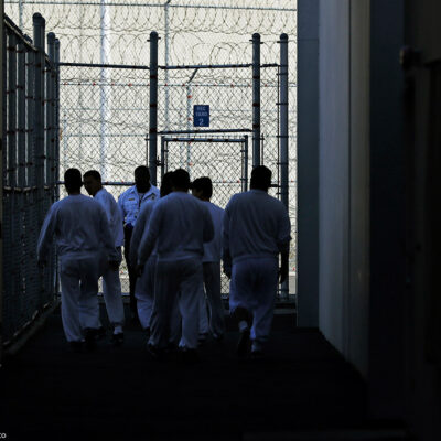 Detainees walk toward a fenced recreation area inside of an ICE detention facility in Washington state.