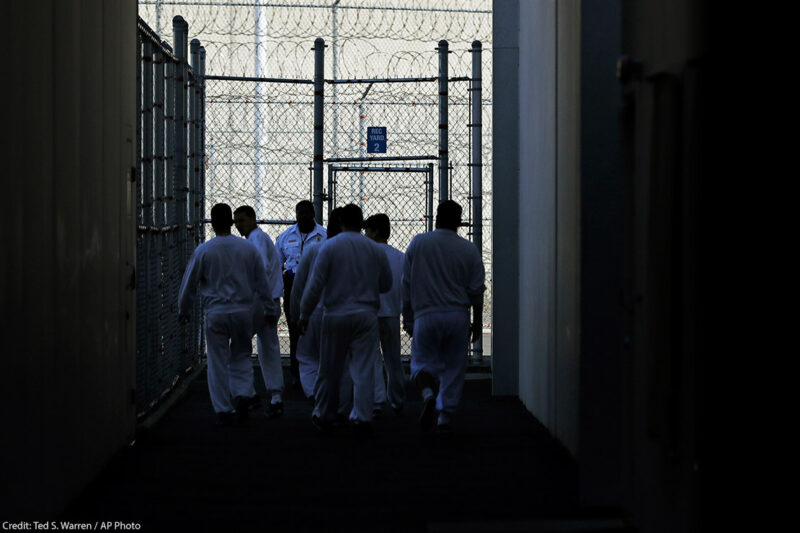 Detainees walk toward a fenced recreation area inside of an ICE detention facility in Washington state.