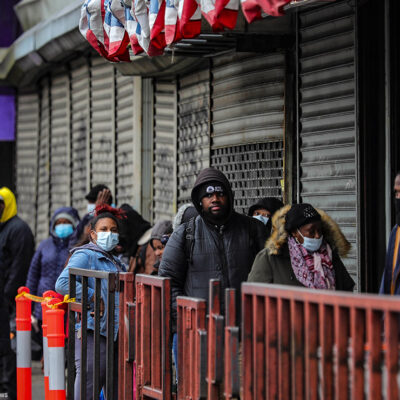 Customers in masks line up outside a grocery store in Brooklyn, NY, waiting to enter after other shoppers have left, because of social distancing efforts during the coronavirus outbreak.