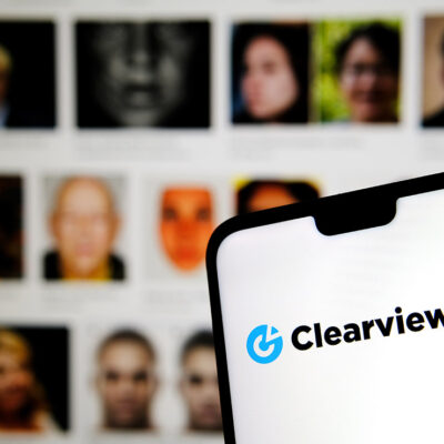 Clearview AI facial recognition software logo on the glowing screen and blurred faces from social media on the background