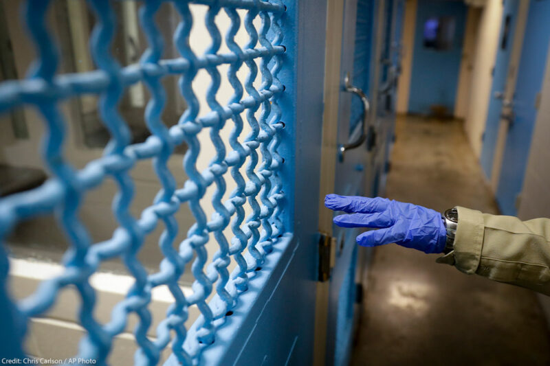 A gloved hand points to a holding cell in a Los Angeles jail.