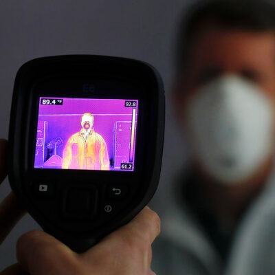 An infrared camera is shown scanning a person for elevated body temperature.