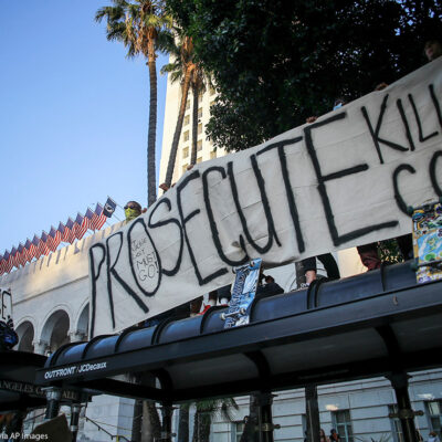 Protesters hold a banner that says, "Prosecute Killer Cops" in front of Los Angeles City Hall during the demonstration.