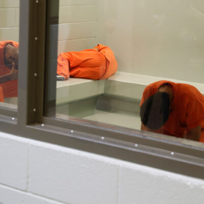 Three detainees waiting together inside a room to be processed at a detention facility.