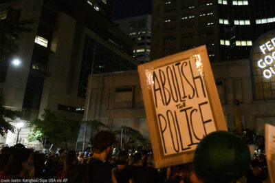 A group of protesters with one holding a sign with the text, "Abolish the Police."