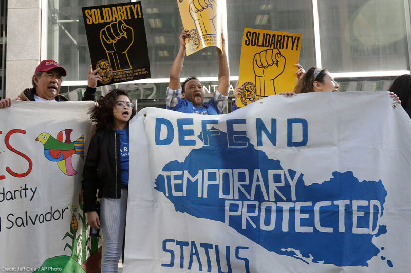 Supporters of temporary protected status immigrants hold signs and cheer at a rally in support of a program that lets immigrants live and work legally in the United States.