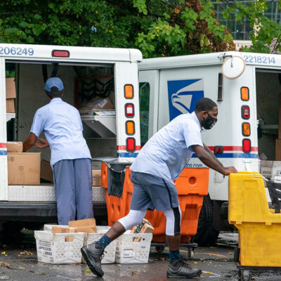 Letter carriers load mail trucks for deliveries at a U.S. Postal Service facility.