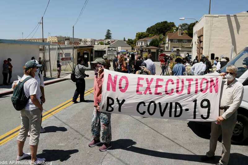 A sign reading "No Executions by Covid-19" is seen at a protest