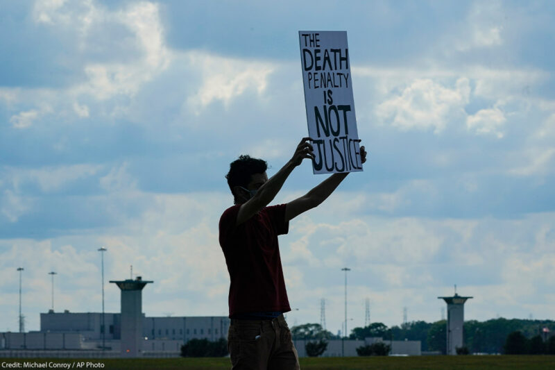 A death penalty protestor carries a sign that reads "the death penalty is not justice."